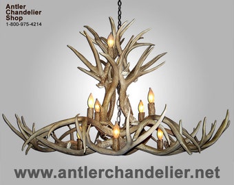 May include: A large antler chandelier with multiple light bulbs. The chandelier is made of natural antlers and has a rustic, natural look. The chandelier is hanging from a chain and has a rustic, natural look.