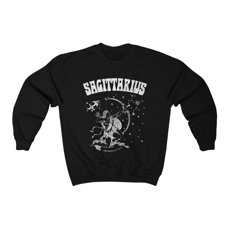 May include: Black sweatshirt featuring a white Sagittarius zodiac design. The graphic depicts an archer with a bow and arrow, the word "SAGITTARIUS", and constellation details. The sweatshirt has a crew neck.
