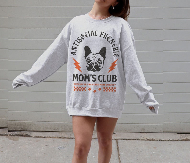 May include: Gray sweatshirt with a black and white graphic of a French bulldog. The graphic says "Antisocial Frenchie Mom's Club" with a lightning bolt on each side of the text. The text "Exclusive Frenchie Mom Society" is below the graphic.