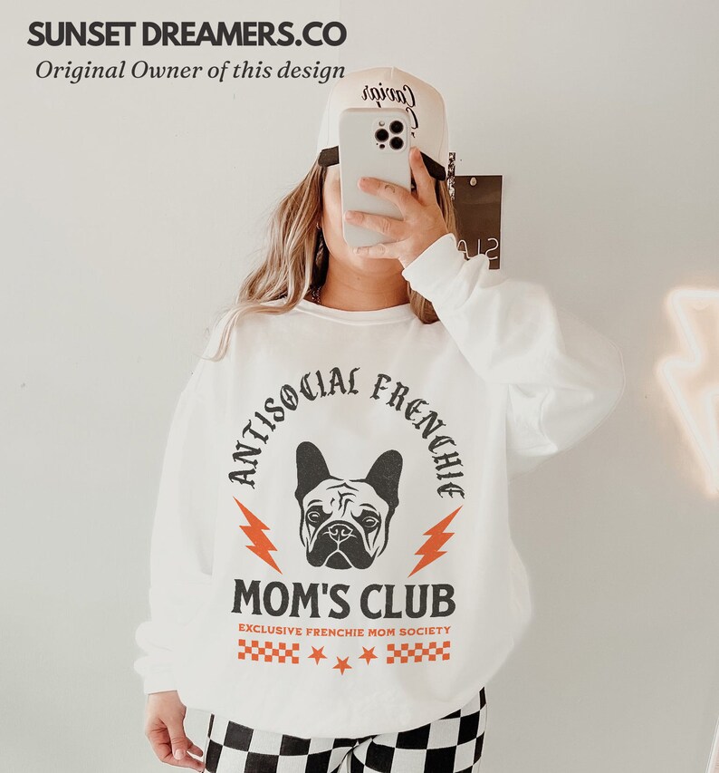 May include: White sweatshirt with a black and white graphic of a French bulldog with the text "Antisocial Frenchie Mom's Club Exclusive Frenchie Mom Society" in orange and black.