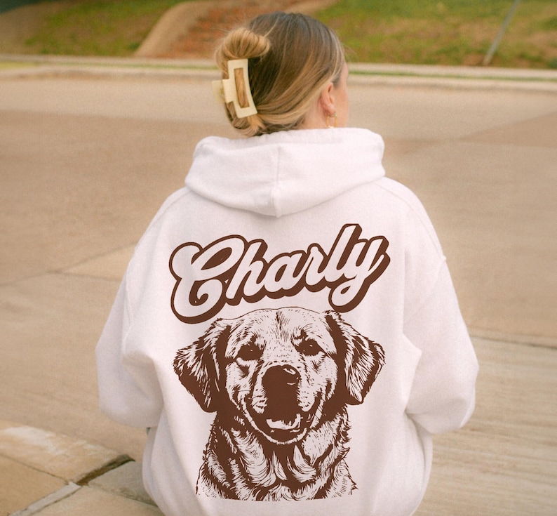May include: White hoodie with a brown illustration of a dog and the name "Charly" in brown text.