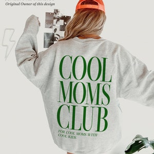 May include: Gray sweatshirt with the text "COOL MOMS CLUB" in green letters. Below the text is the phrase "FOR COOL MOMS WITH COOL KIDS" in smaller green letters.