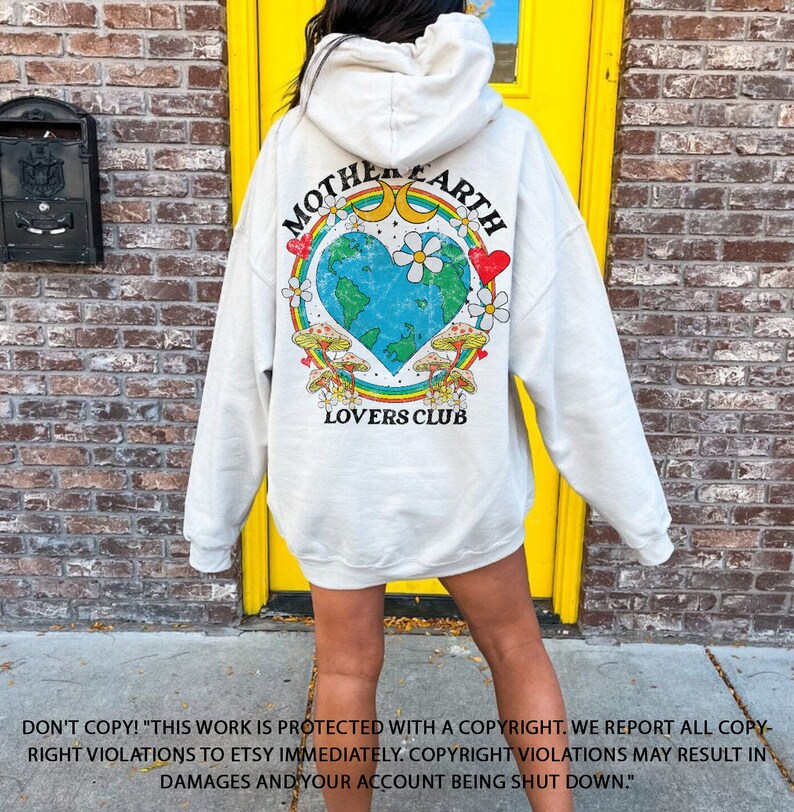 May include: A white hoodie with a graphic print of a heart-shaped Earth with a rainbow, mushrooms, and the text "Mother Earth Lovers Club".
