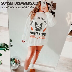 May include: White sweatshirt with a graphic of a French bulldog and the text "Antisocial Frenchie Mom's Club Exclusive Frenchie Mom Society".