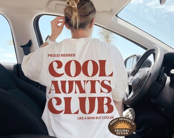Puede incluir: Camiseta blanca con texto rojo que dice "Proud Member Cool Aunts Club Like a Mom But Cooler" con un pequeño logotipo en la esquina inferior derecha que dice "Sunset Dreamers Co. Original Design".