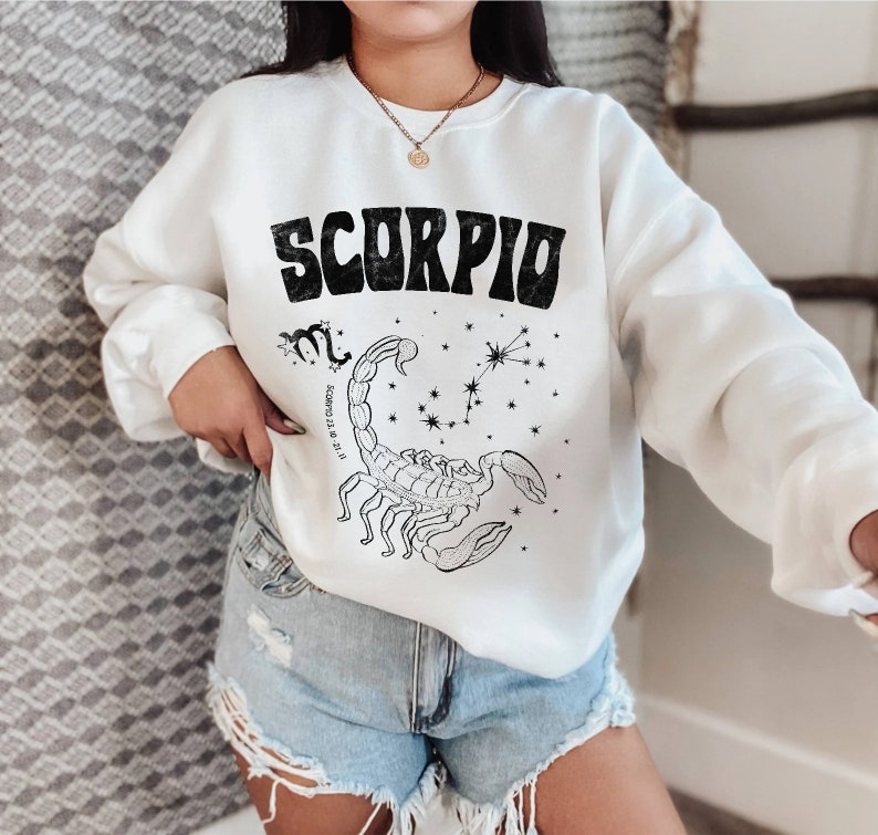 May include: White sweatshirt with a black graphic of a scorpion and the word "Scorpio" in a retro font. The graphic also includes the constellation Scorpio and the dates "October 23 - November 21".