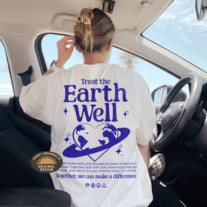 May include: White t-shirt with a blue graphic print of the Earth with the text "Treat the Earth Well" and a heart shape around the Earth. The text "Together, we can make a difference" is printed below the graphic.