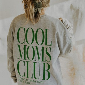May include: Gray sweatshirt with the text "COOL MOMS CLUB" in green letters. The text "FOR COOL MOMS WITH COOL KIDS" is printed below the main text.