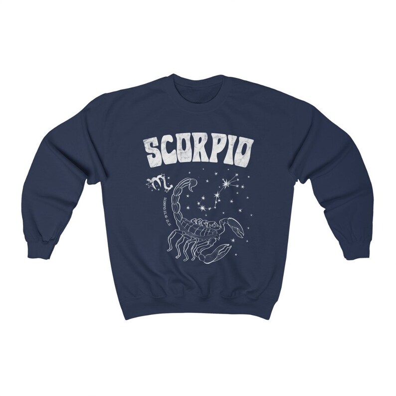 May include: Navy blue sweatshirt with a white graphic of a scorpion and the word "SCORPIO" in a retro font. The graphic also includes the astrological symbol for Scorpio and the dates October 23 - November 21.