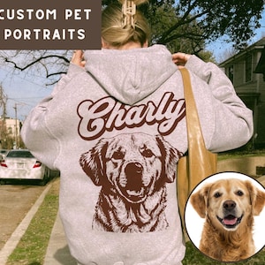 May include: A gray hoodie with a brown dog illustration and the name "Charly" printed on the back. The dog is a golden retriever with a brown nose and brown eyes. The hoodie has a hood and a zipper.