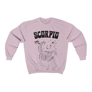 May include: A light pink sweatshirt with a black graphic print of a scorpion and the word "SCORPIO" in a retro font.