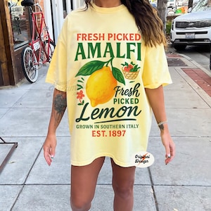 May include: A yellow t-shirt with a graphic of a lemon and the text "Fresh Picked Amalfi Lemon Grown in Southern Italy Est. 1897".