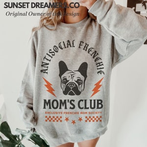 May include: Gray sweatshirt with a black and white graphic of a French bulldog. The graphic says "Antisocial Frenchie Mom's Club" with the text "Exclusive Frenchie Mom Society" underneath.