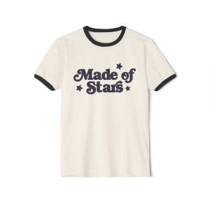 May include: A white t-shirt with a black ringer neck and a navy blue graphic that says "Made of Stars" with stars on either side of the text.