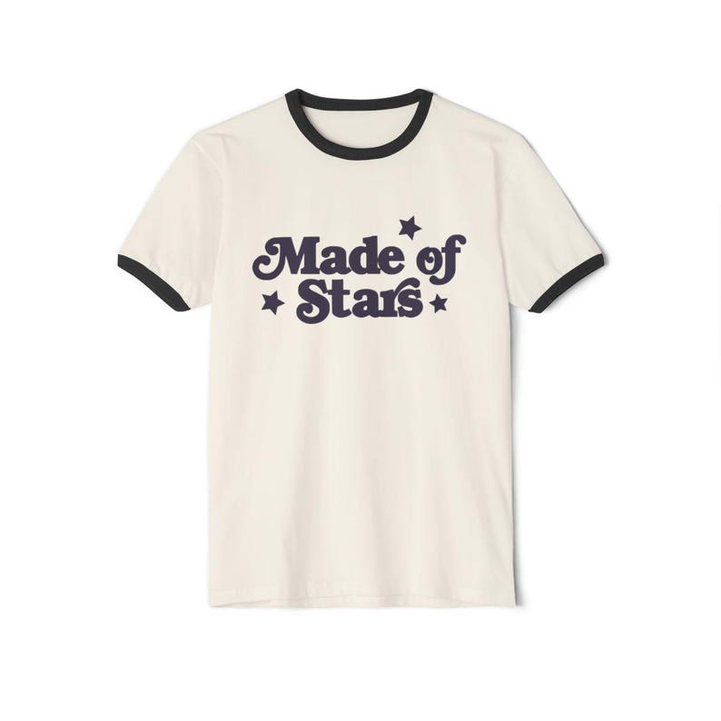 May include: A white t-shirt with a black ringer neck and a navy blue graphic that says "Made of Stars" with stars on either side of the text.