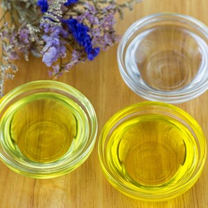 Peut inclure: Trois petits bols en verre sur une surface en bois. Deux bols contiennent un liquide jaune, et un bol est vide.