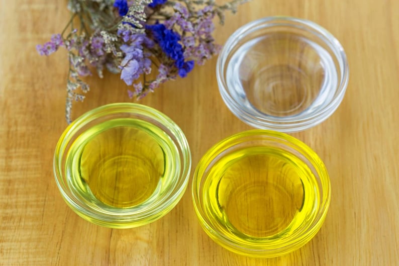 Peut inclure: Trois petits bols en verre sur une surface en bois. Deux bols contiennent un liquide jaune, et un bol est vide.