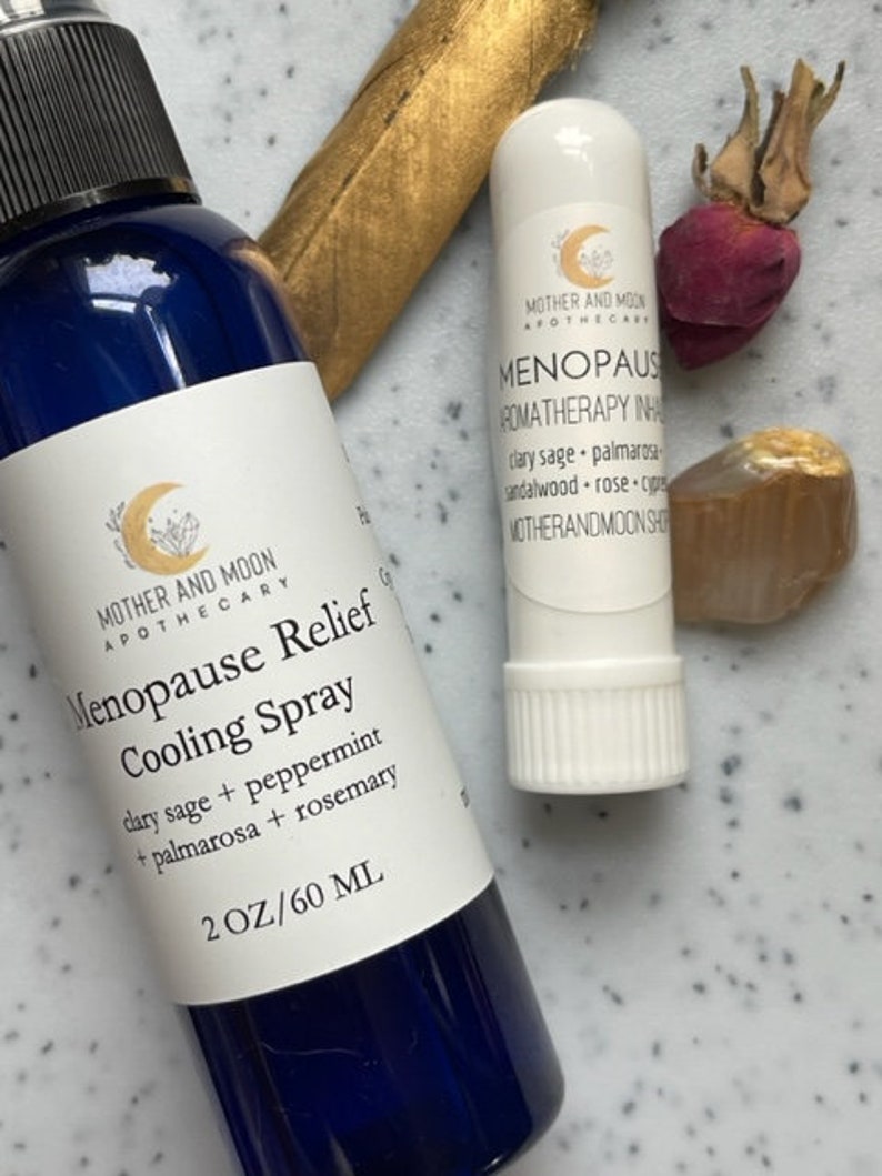 May include: Two bottles of aromatherapy products for menopause relief. A blue spray bottle labeled "Menopause Relief Cooling Spray" with the ingredients listed. A white roll-on bottle labeled "Menopause Aromatherapy Inhaler" with the ingredients listed.