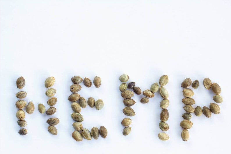 May include: The word "HEMP" spelled out using hemp seeds on a white background.
