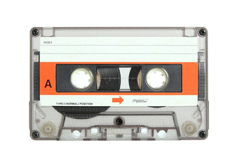 May include: A clear plastic cassette tape with an orange label. The label says "Type I Normal Position" and "Compact Cassette". The tape is labeled with the letter "A" and has a black index.