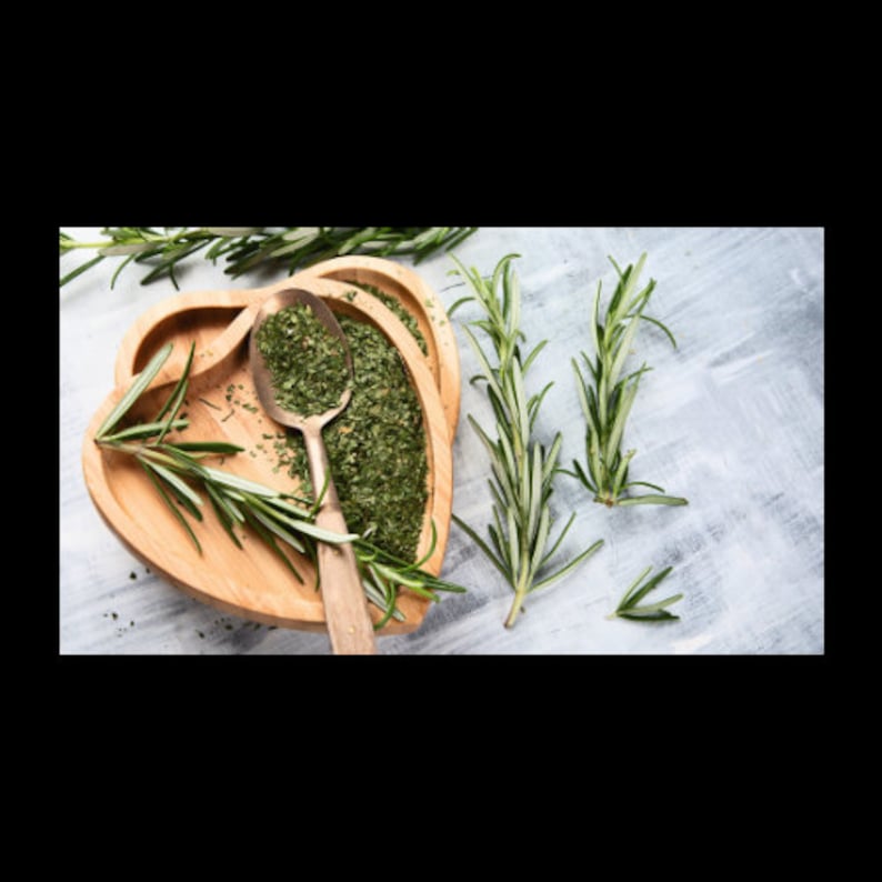 May include: A wooden heart-shaped bowl filled with dried rosemary and a spoon. The bowl is surrounded by sprigs of fresh rosemary on a light gray background.