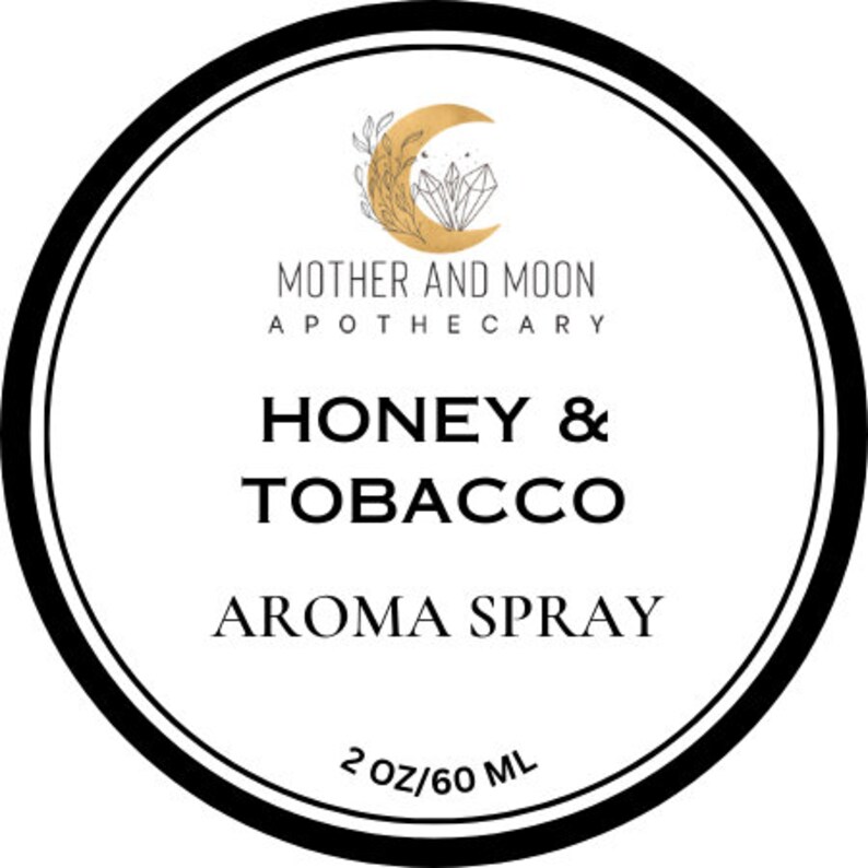 May include: A white round label with black text and a gold illustration of a crescent moon and crystals. The text reads "Mother and Moon Apothecary", "Honey & Tobacco", "Aroma Spray", and "2 oz/60 ml".