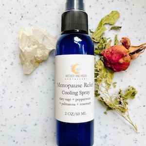 May include: A blue glass bottle with a spray nozzle, labeled "Menopause Relief Cooling Spray" with the ingredients clary sage, peppermint, palmarosa, and rosemary. The bottle is 2 ounces or 60 milliliters.