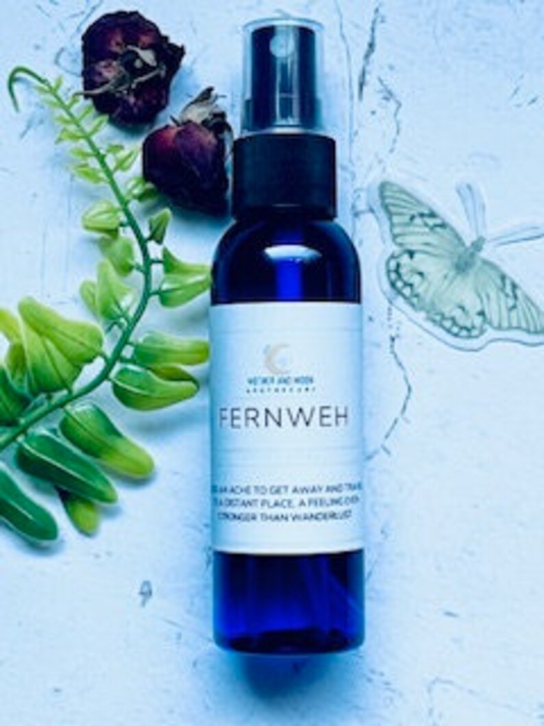 May include: A blue glass bottle with a spray nozzle, labeled "Fernweh" and "The urge to get away and travel to a distant place, a feeling stronger than wandering lust."