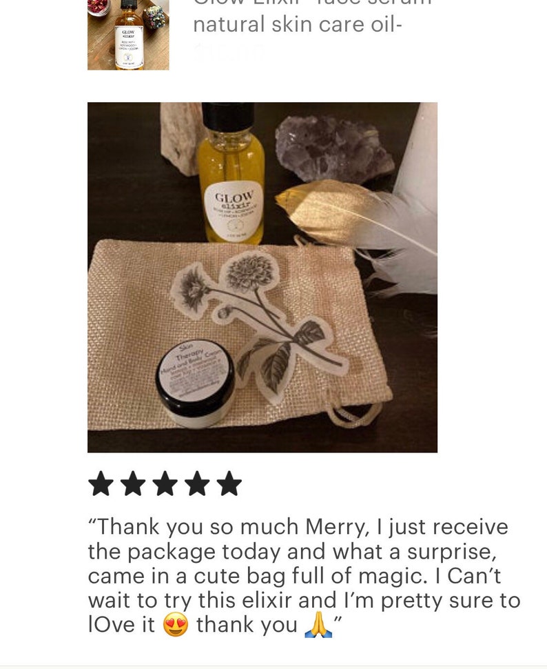 Peut inclure: Un petit sac en toile de jute avec un motif floral, contenant un petit pot de cr&egrave;me de soin pour la peau et un flacon en verre d'&eacute;lixir de soin du visage. Le flacon porte une &eacute;tiquette noire avec les mots "Glow Elixir" imprim&eacute;s dessus. L'image comprend &eacute;galement une plume et un cristal.