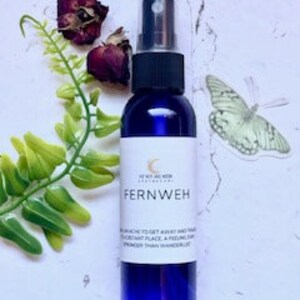 May include: A blue glass bottle with a spray nozzle, labeled "Fernweh" and "To enhance to get away and travel to distant place, a feeling and strength than wanderlust".