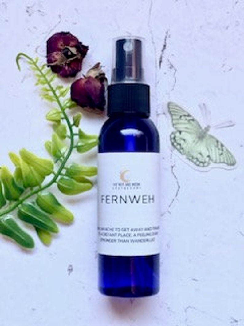 May include: A blue glass bottle with a spray nozzle, labeled "Fernweh" and "To enhance to get away and travel to distant place, a feeling and strength than wanderlust".