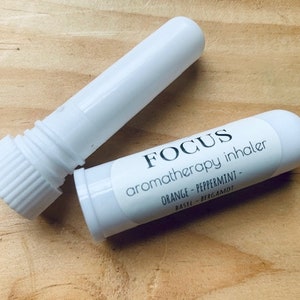 May include: White aromatherapy inhaler with a label that reads "FOCUS aromatherapy inhaler ORANGE - PEPPERMINT - BASIL - BERGAMOT"