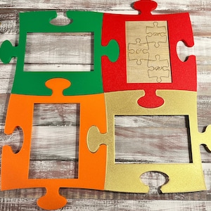 May include: A colorful puzzle-shaped wall decor piece. The design features four puzzle pieces in green, orange, red, and gold. The red piece has a wooden insert with the letters "sec" and "omc" in a puzzle design.