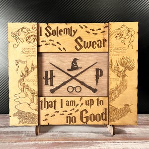 May include: Wooden sign with the text "I Solemnly Swear That I Am Up To No Good." The sign features a map, footprints, and illustrations of a hat, glasses, and wands. The sign is supported by a wooden stand.