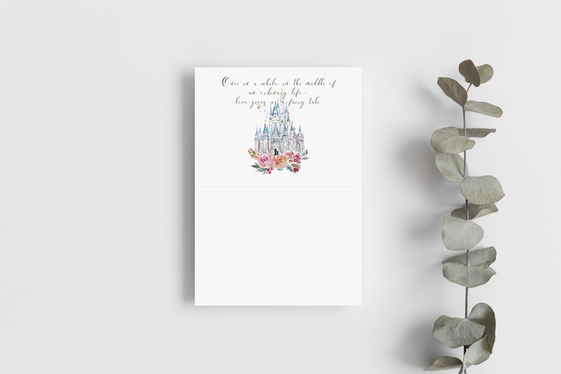 May include: White folded card with a watercolor illustration of a fairytale castle, surrounded by pink and peach flowers. The card has the text: "Once in a while, in the middle of an ordinary life... love gives us a fairy tale."