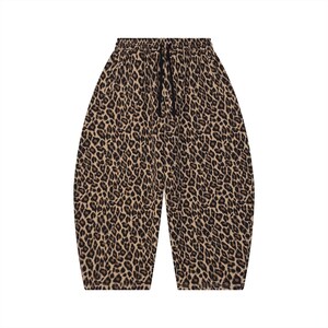 May include: A pair of loose-fitting pants featuring a brown and black leopard print pattern. The garment has an elasticized waistband with a black drawstring tie centered at the front. The legs have a wide, tapered silhouette that ends at the calf.