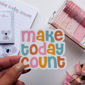 May include: A sticker with the text "make today count" in colorful, rounded letters. The letters are pink, orange, yellow, and blue. The sticker is on a white background.