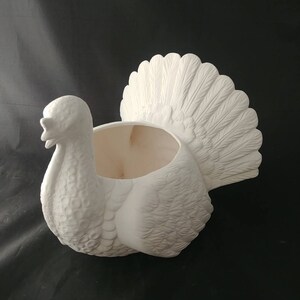 May include: White ceramic turkey planter with a detailed feathered tail and a hollow body for planting.