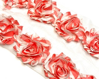 May include: A decorative ribbon featuring fabric roses in coral and white stripes. The roses are attached to a white mesh backing, creating a delicate and textured design. Ideal for crafting and embellishments.