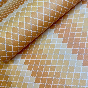 May include: A close-up of a fabric with a geometric pattern. The fabric is a light brown color with a white pattern of interlocking squares. The fabric has a subtle texture.