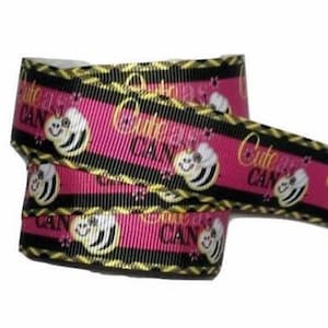 May include: Pink ribbon with a repeating pattern of smiling cartoon bees and the words "Cute as CAN be" in gold. The ribbon has black and gold striped borders.