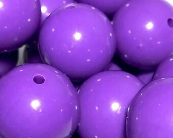 May include: Close-up of several large, round, glossy purple beads. Each bead has a hole drilled through it. The beads are clustered together, creating a visually appealing texture and color contrast.