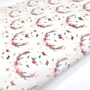 May include: White fabric with a repeating pattern of brown antlers and pink flowers.