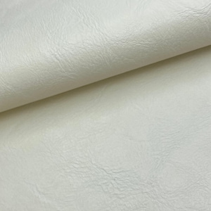 May include: Close-up of a white faux leather fabric with a textured surface.