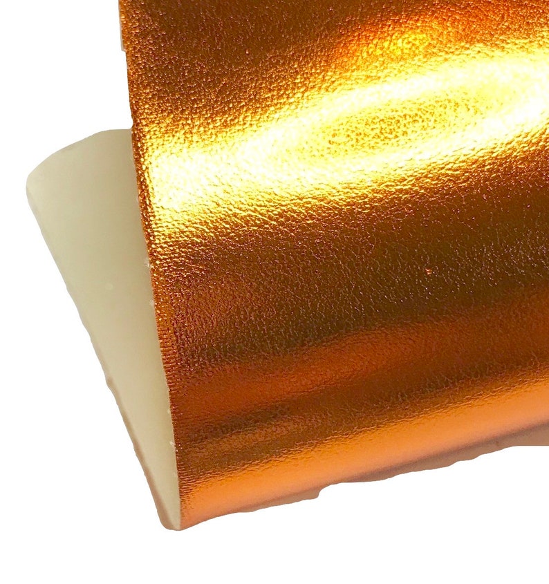 May include: A close-up of a piece of metallic gold fabric with a textured surface.