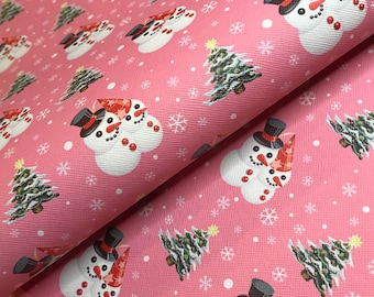 Könnte beinhalten: Rosa Weihnachtsmotiv-Stoff mit sich wiederholenden Mustern von Schneemännern, Weihnachtsbäumen und Schneeflocken. Die Schneemänner tragen schwarze Zylinder und rote Schals. Die Weihnachtsbäume sind grün mit gelben Sternen. Weiße Schneeflocken sind verstreut.