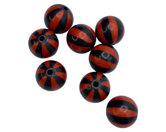 May include: A collection of eight round beads. Each bead is a reddish-orange color with black stripes. The beads have a hole through the center, suggesting they are for stringing. The beads are scattered against a white background.