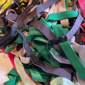 Puede incluir: Un mont&oacute;n de gomas el&aacute;sticas de colores en varios tonos de verde, negro, beige, rosa y amarillo. Las gomas el&aacute;sticas son de diferentes anchos y est&aacute;n dispuestas en un patr&oacute;n aleatorio.