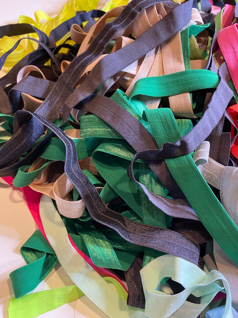 Puede incluir: Un mont&oacute;n de gomas el&aacute;sticas de colores en varios tonos de verde, negro, beige, rosa y amarillo. Las gomas el&aacute;sticas son de diferentes anchos y est&aacute;n dispuestas en un patr&oacute;n aleatorio.