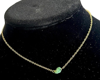 May include: A delicate gold chain necklace with a single, small, green gemstone pendant.